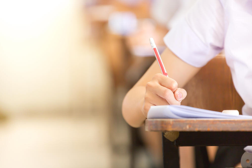 Student Writing on Desk with a pencil
